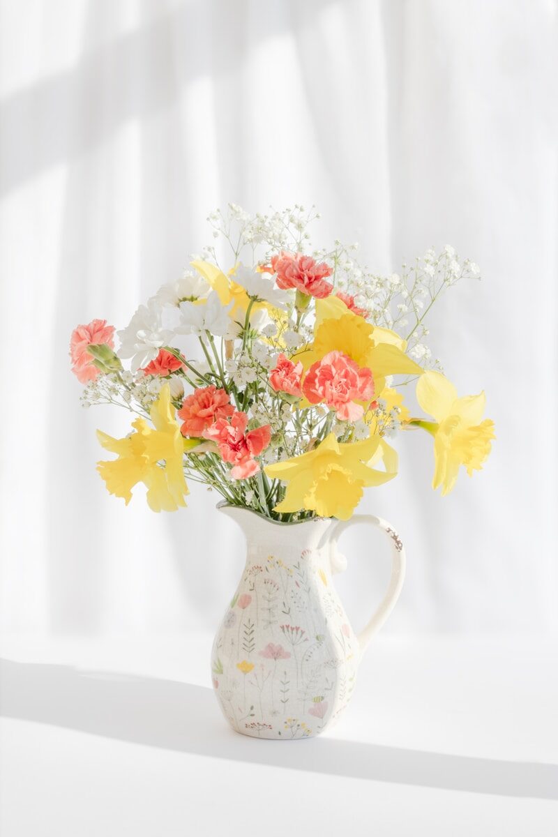 A vase of yellow daffodils and pink carnations